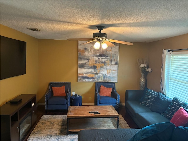 living room featuring ceiling fan, a textured ceiling, and dark hardwood / wood-style flooring