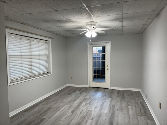 empty room featuring ceiling fan, a drop ceiling, and light wood-type flooring