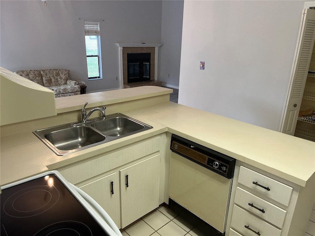 kitchen featuring dishwasher, kitchen peninsula, sink, range, and a tiled fireplace