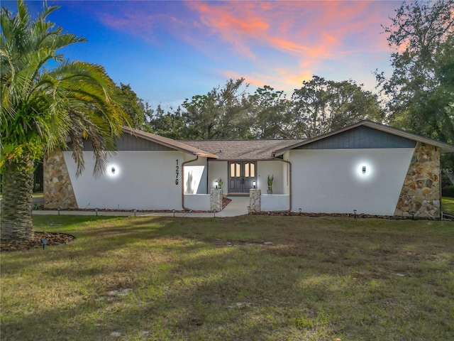 back house at dusk with a lawn