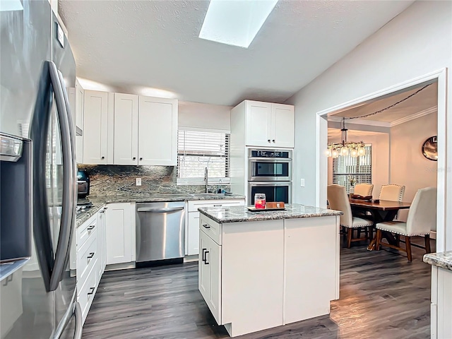 kitchen with a center island, light stone counters, white cabinetry, and appliances with stainless steel finishes