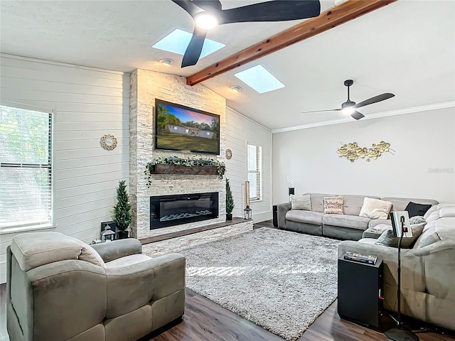 living room featuring a stone fireplace, wood walls, vaulted ceiling with skylight, and dark wood-type flooring