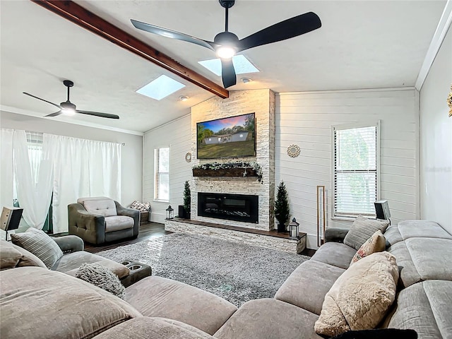 living room with lofted ceiling with skylight, wooden walls, hardwood / wood-style flooring, ceiling fan, and a fireplace