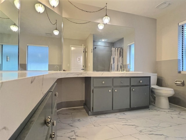 bathroom featuring vanity, toilet, walk in shower, and tile walls