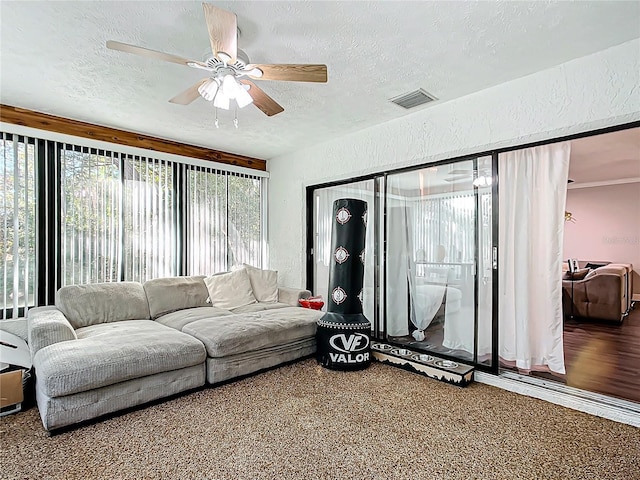 living room featuring ceiling fan, carpet floors, and a textured ceiling