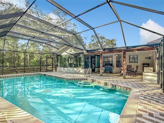 view of swimming pool with glass enclosure, ceiling fan, and a patio area