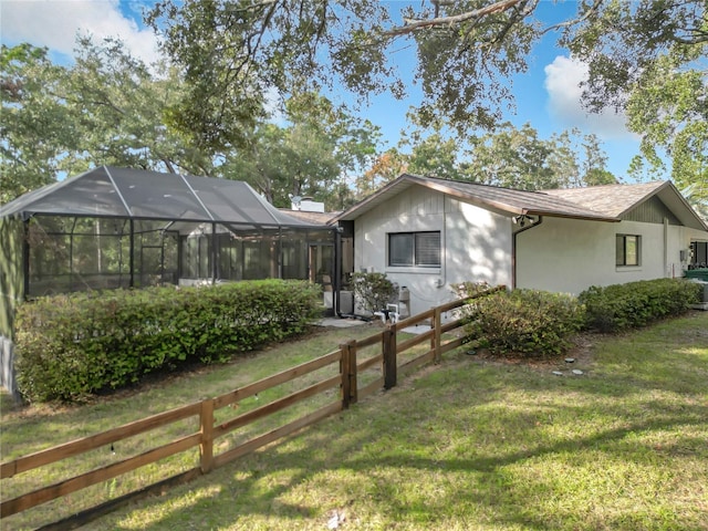 back of property featuring glass enclosure and a yard