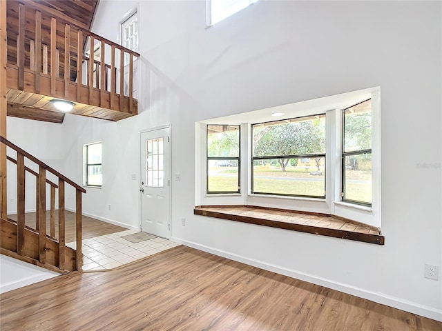 entryway with light hardwood / wood-style floors and a towering ceiling