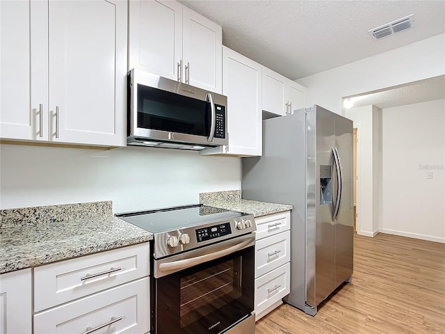 kitchen featuring white cabinets, a textured ceiling, appliances with stainless steel finishes, light hardwood / wood-style floors, and light stone counters