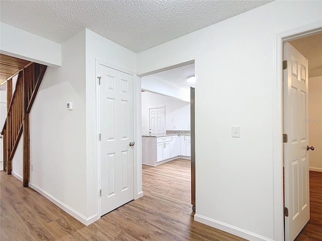 hallway with hardwood / wood-style flooring and a textured ceiling