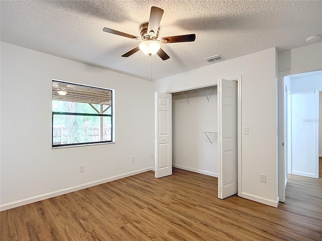 unfurnished bedroom with a closet, a textured ceiling, hardwood / wood-style flooring, and ceiling fan