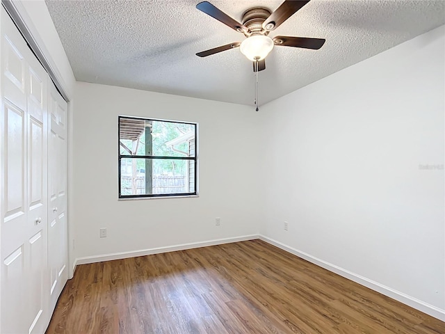 unfurnished bedroom featuring ceiling fan, a closet, hardwood / wood-style floors, and a textured ceiling