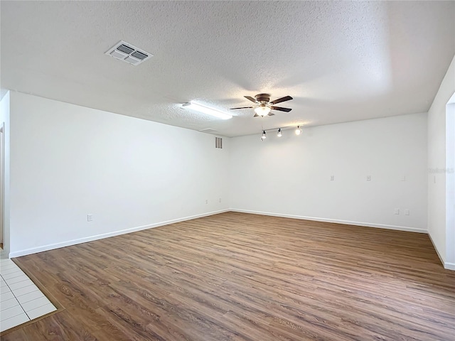 spare room featuring rail lighting, wood-type flooring, and a textured ceiling