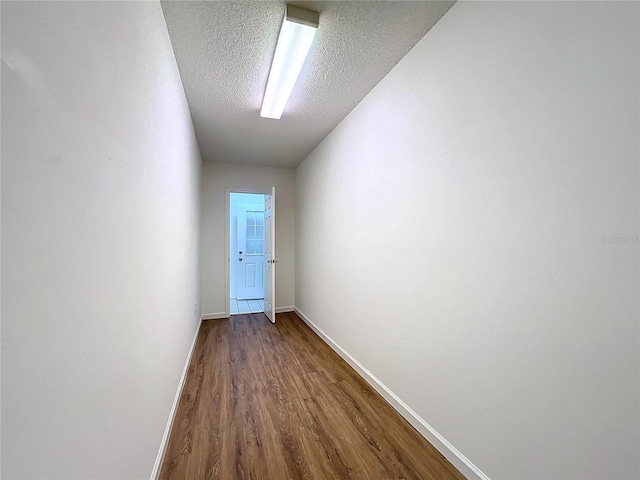 corridor with wood-type flooring and a textured ceiling