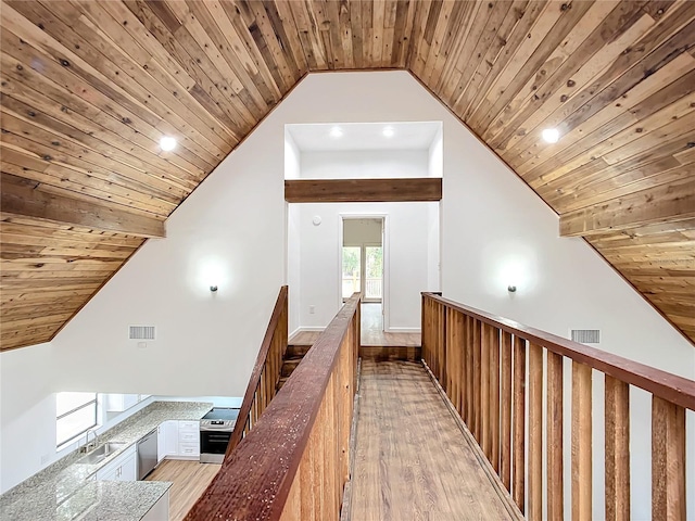 corridor featuring lofted ceiling, wooden ceiling, sink, and light hardwood / wood-style flooring