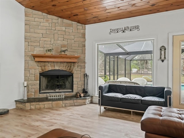 living room featuring vaulted ceiling, hardwood / wood-style flooring, a stone fireplace, and wood ceiling