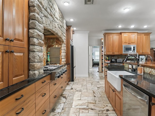 kitchen with sink, stainless steel appliances, tasteful backsplash, crown molding, and dark stone counters