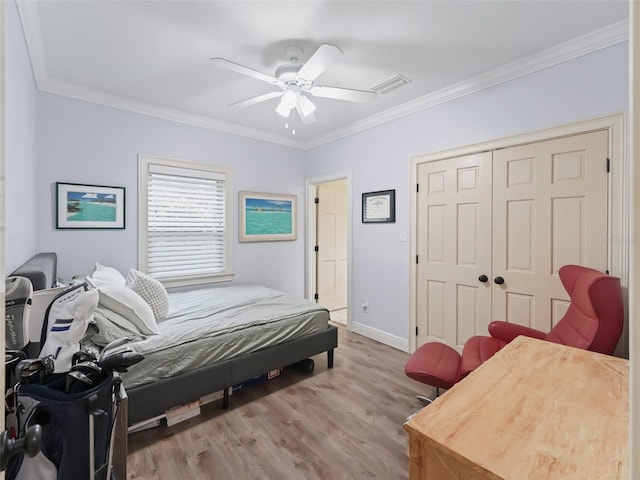 bedroom featuring ceiling fan, light hardwood / wood-style floors, ornamental molding, and a closet