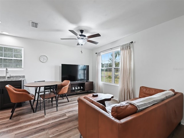 living room featuring ceiling fan, light wood-type flooring, and sink