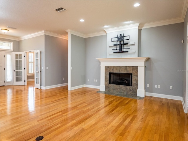 unfurnished living room with a tile fireplace, light hardwood / wood-style flooring, and crown molding