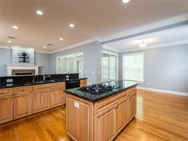 kitchen featuring black appliances, sink, dark stone countertops, a center island, and light hardwood / wood-style floors