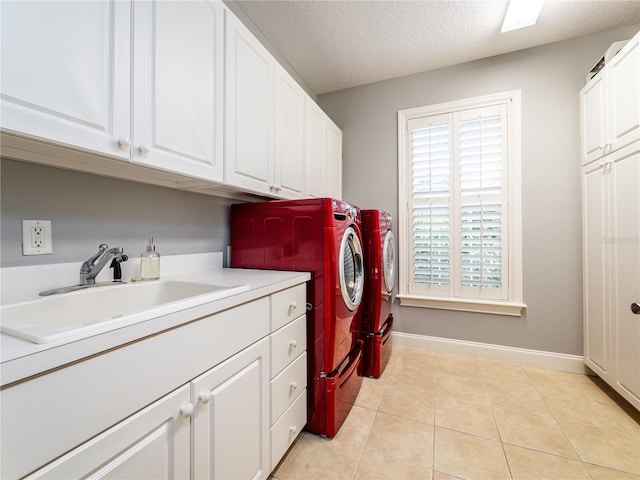 washroom featuring washing machine and clothes dryer, sink, cabinets, a textured ceiling, and light tile patterned floors