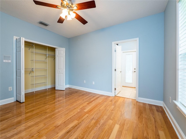 unfurnished bedroom featuring a closet, a textured ceiling, light hardwood / wood-style floors, and ceiling fan