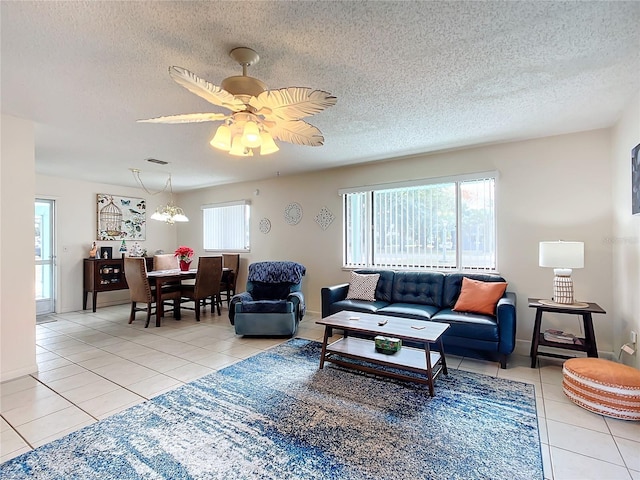 tiled living room featuring a textured ceiling and ceiling fan with notable chandelier