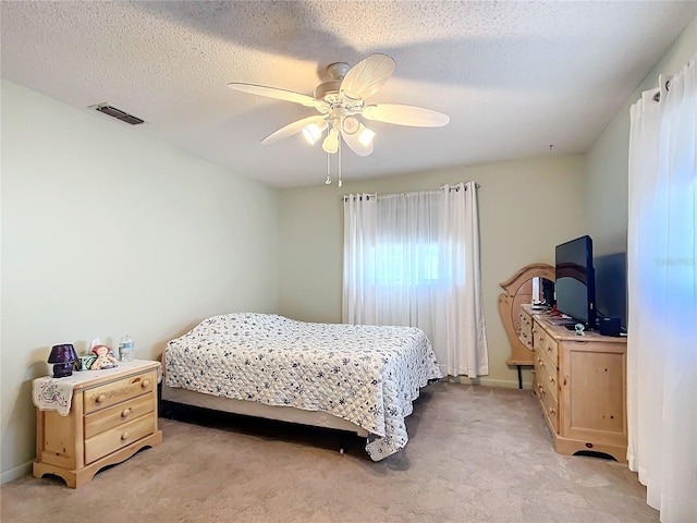 bedroom featuring a textured ceiling, light colored carpet, and ceiling fan