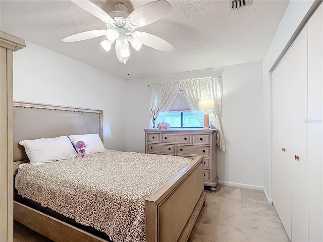 bedroom with ceiling fan, a closet, light carpet, and a textured ceiling