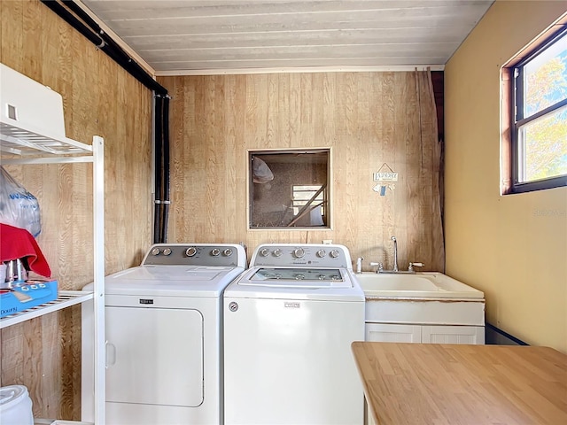 clothes washing area featuring washing machine and dryer, wooden walls, sink, and wooden ceiling