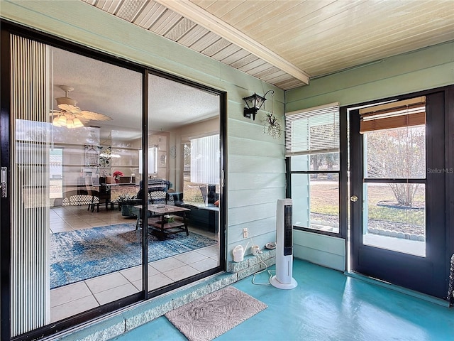 doorway featuring wooden walls, ceiling fan, concrete flooring, and wooden ceiling