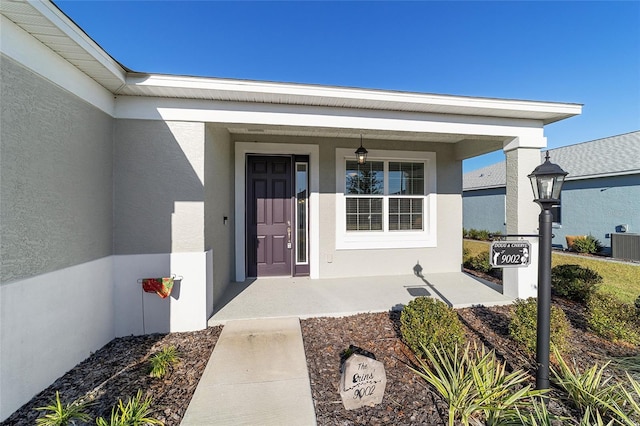 doorway to property featuring covered porch and central AC