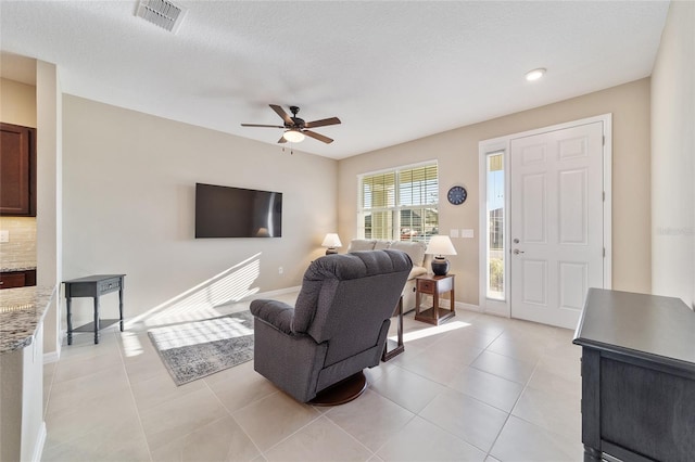 living room with light tile patterned floors, a textured ceiling, and ceiling fan