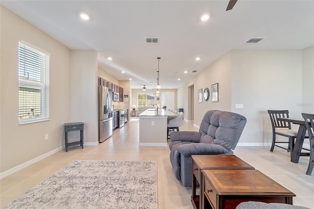 tiled living room featuring ceiling fan, sink, and a healthy amount of sunlight