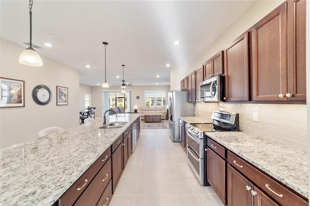 kitchen with pendant lighting, sink, decorative backsplash, appliances with stainless steel finishes, and light stone counters