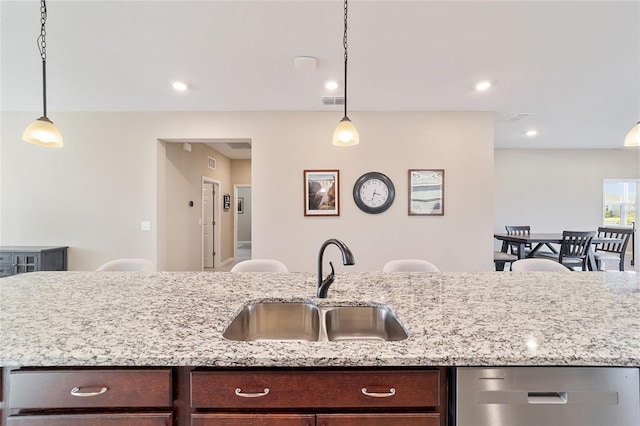 kitchen with dark brown cabinets, stainless steel dishwasher, hanging light fixtures, and sink