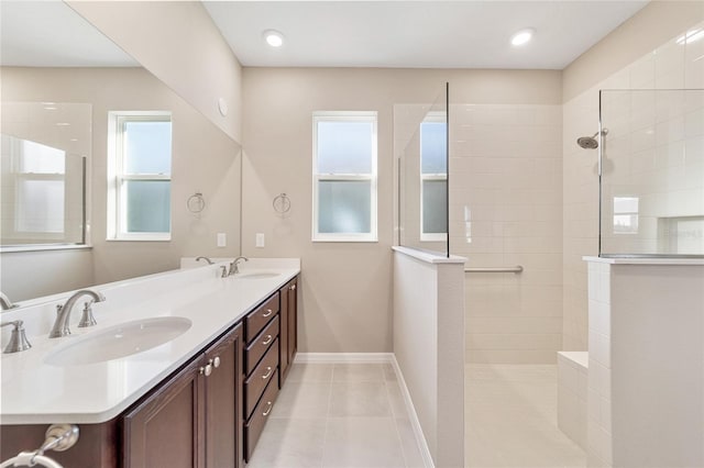 bathroom with tile patterned flooring, a tile shower, and vanity