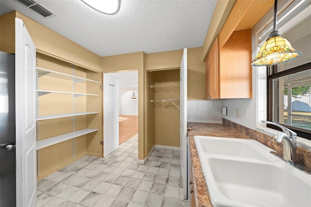 bathroom with a textured ceiling, tasteful backsplash, and sink