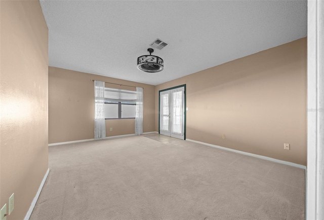 unfurnished bedroom featuring light carpet, french doors, and a textured ceiling