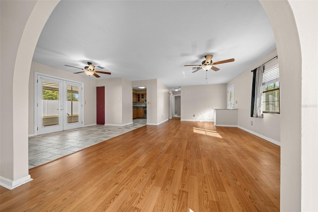 unfurnished living room with ceiling fan, french doors, and light hardwood / wood-style floors