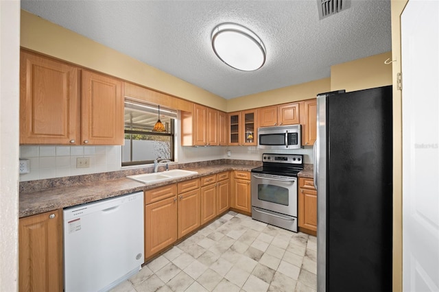 kitchen with appliances with stainless steel finishes, a textured ceiling, tasteful backsplash, and sink