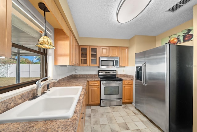 kitchen with decorative backsplash, a textured ceiling, stainless steel appliances, sink, and pendant lighting