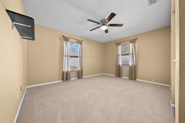 unfurnished room featuring ceiling fan, light colored carpet, and a textured ceiling