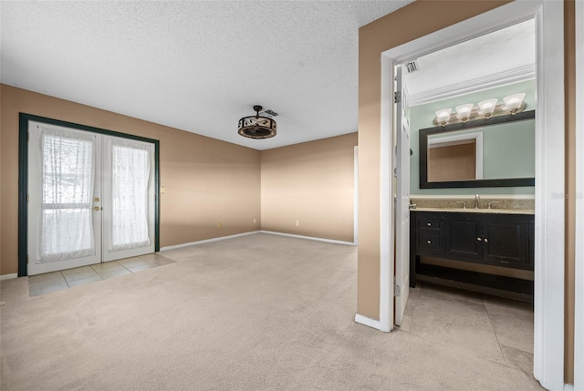 carpeted empty room featuring french doors, a textured ceiling, and sink