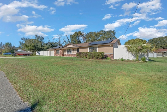 ranch-style home featuring solar panels and a front lawn