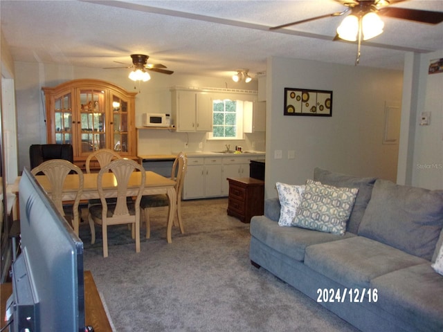 living room featuring a textured ceiling, ceiling fan, sink, and light carpet