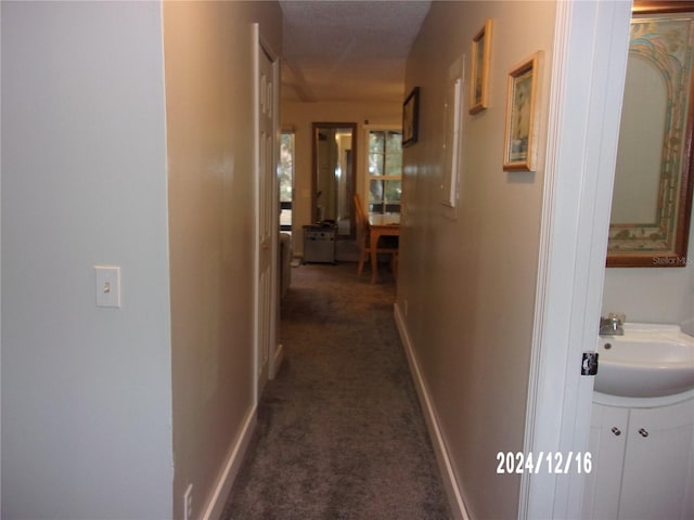 corridor featuring sink and dark colored carpet