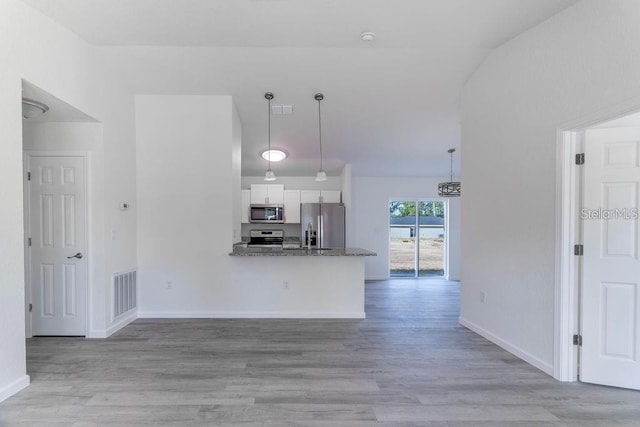 kitchen with kitchen peninsula, decorative light fixtures, appliances with stainless steel finishes, stone countertops, and white cabinetry