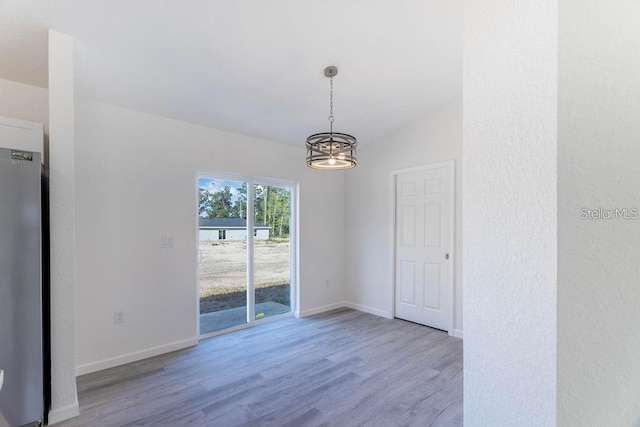 unfurnished dining area with wood-type flooring, lofted ceiling, and an inviting chandelier